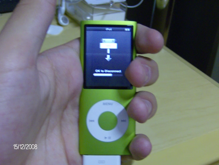 a hand holding a small green and white ipod