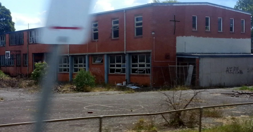 a run down red brick building next to a basketball court