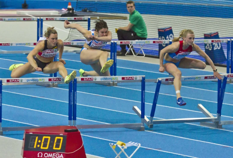 three women in the air jumping over a hurdle