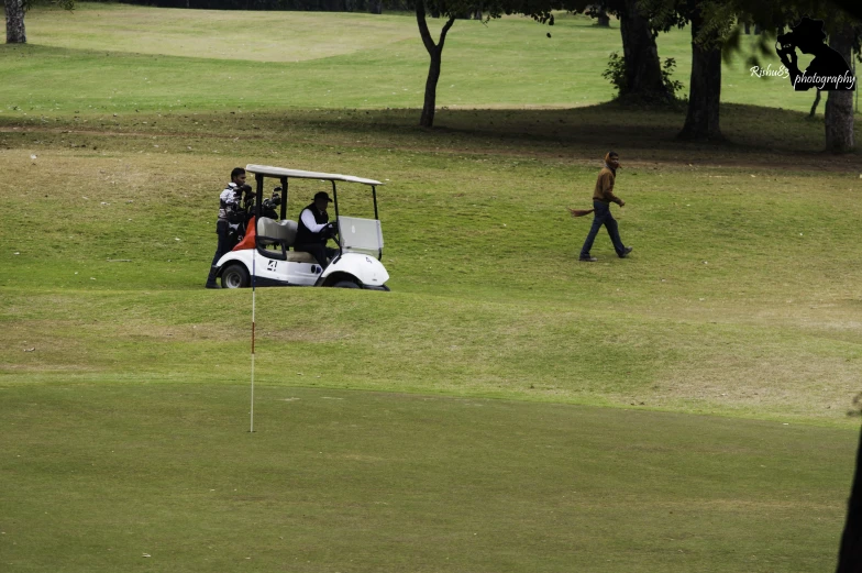 the golf cart is parked in the grass and people are walking toward it