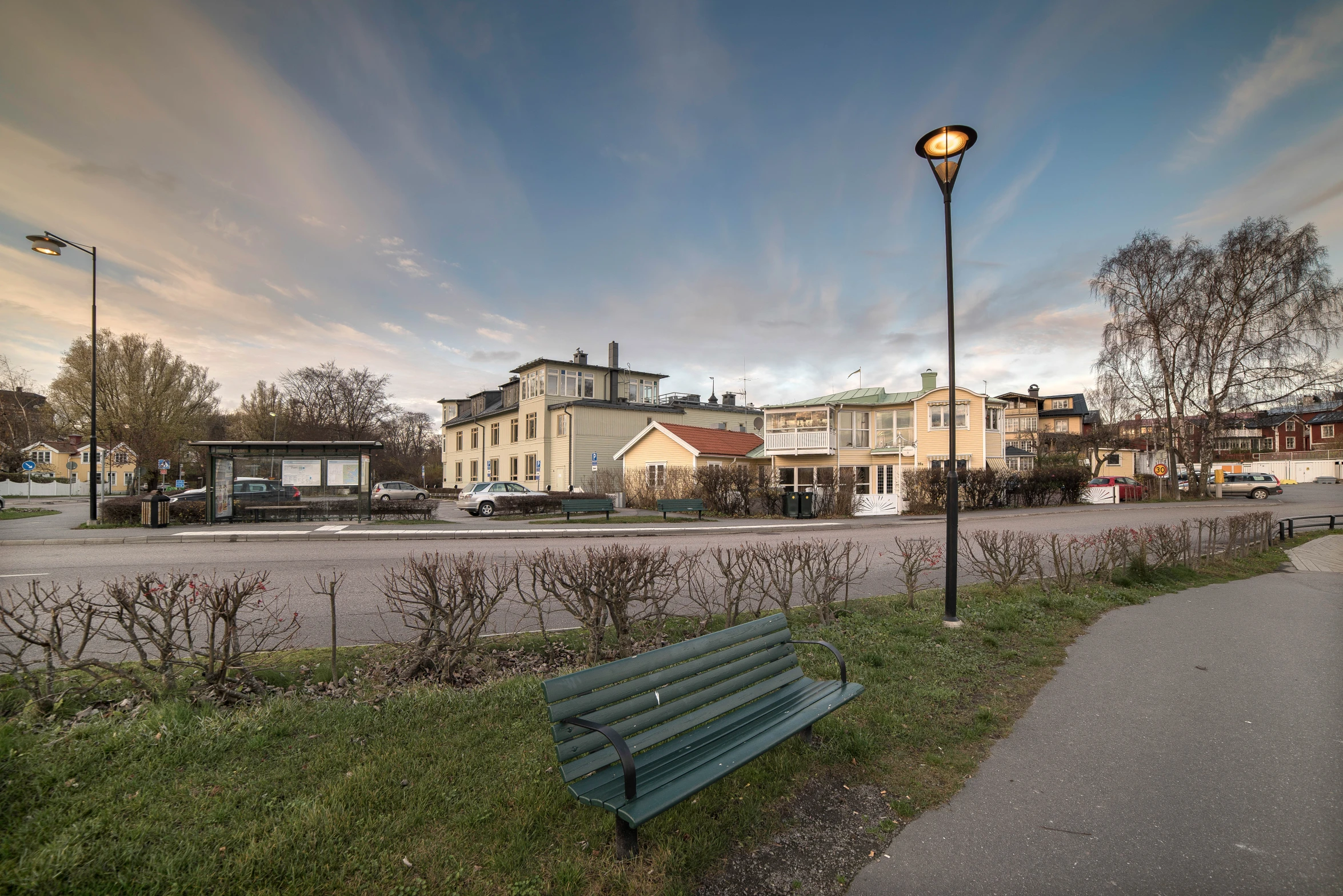 a bench is in the grass near a street