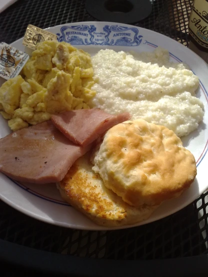 a plate filled with scrambled eggs, ham and biscuits