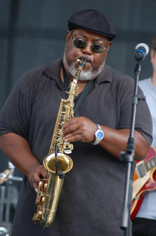 an older man with sunglasses and cap playing saxophone