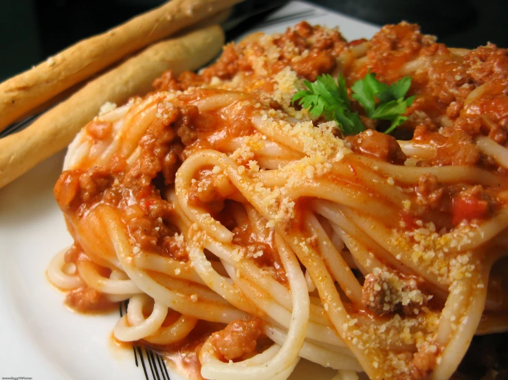 spaghetti and garlic on a white plate with breadsticks