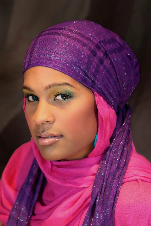 an african woman in a pink hijab with a blue scarf around her neck