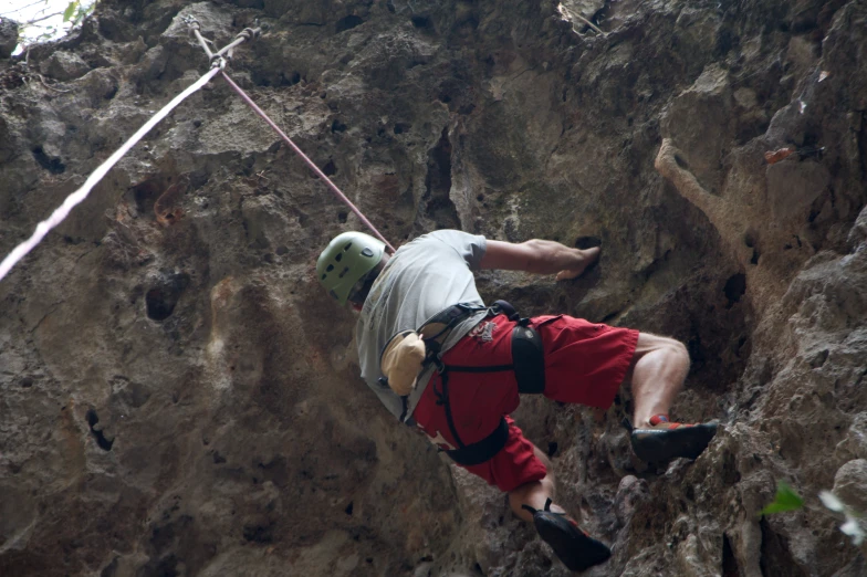 a man hanging from a rock, while holding onto a rope