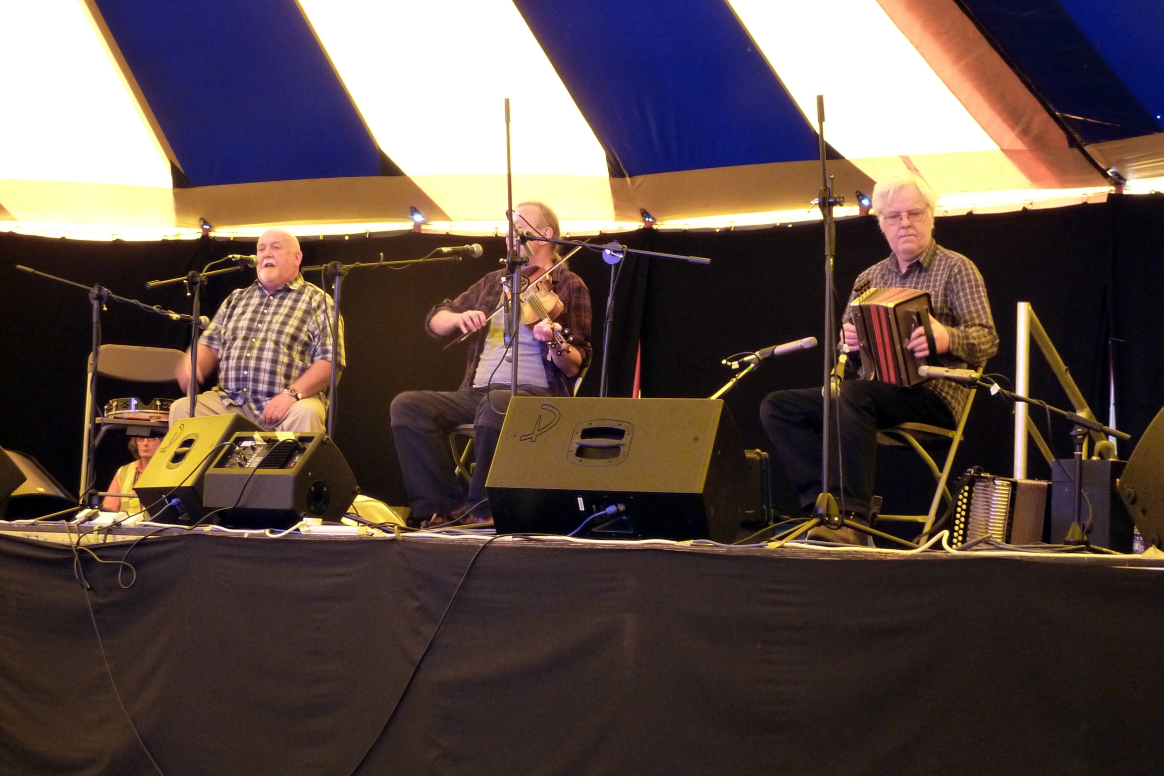 three people sitting on stage playing guitars