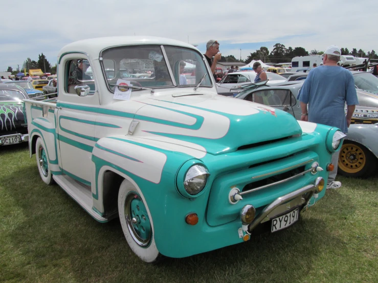 a blue and white truck parked in front of other cars