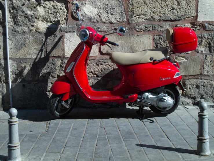 a red scooter is parked near a brick wall