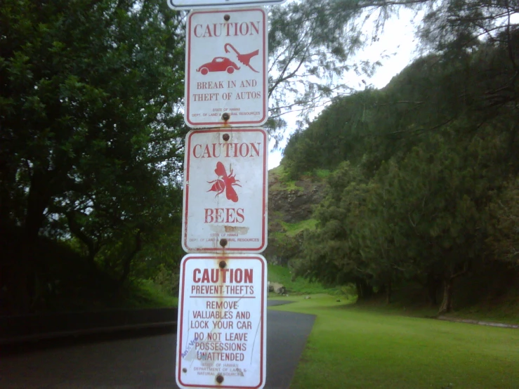 various signs on a metal pole with grass in the background