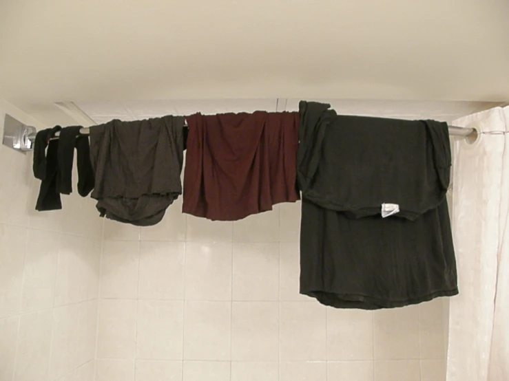 three scarves are hanging on the side of a shower stall