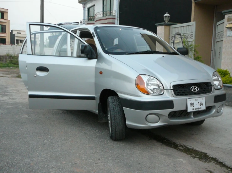 a silver compact van with open hood sitting on the street