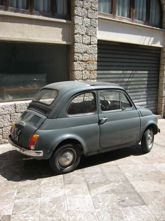 a small blue car sitting in front of a closed garage