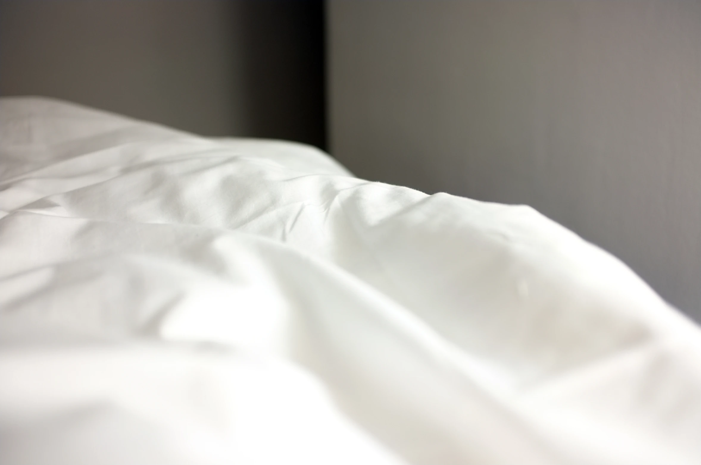 white sheets of a bed with light coming from behind them