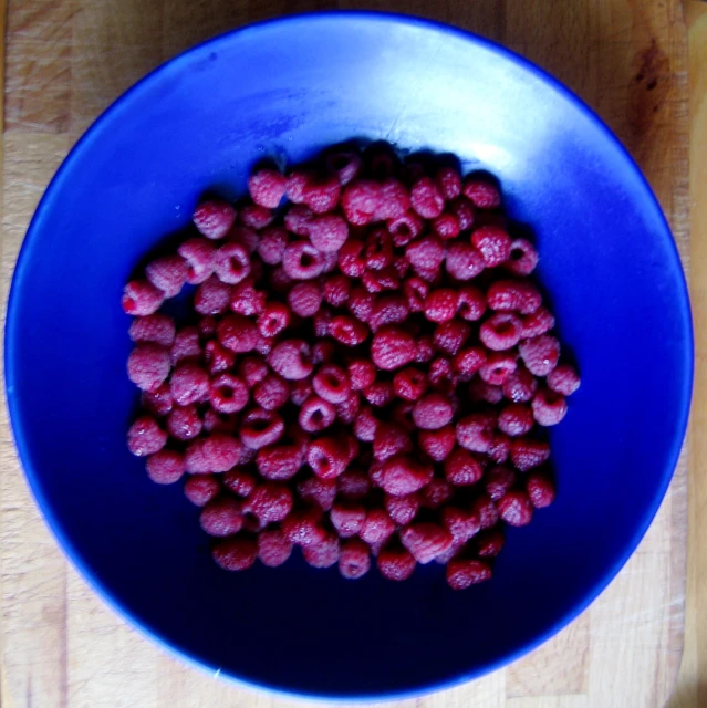 bowl of raspberries on a wooden table top