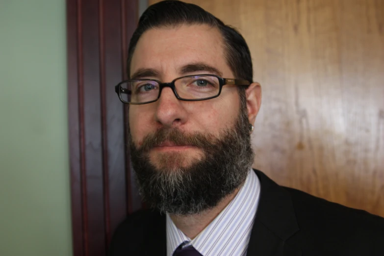 a bearded man wearing glasses is posing for a portrait