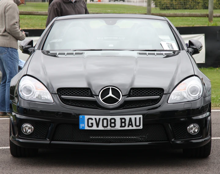 two men are standing in front of a black car