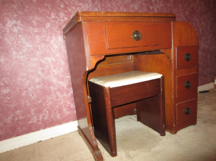 small wooden desk with a white seat underneath it