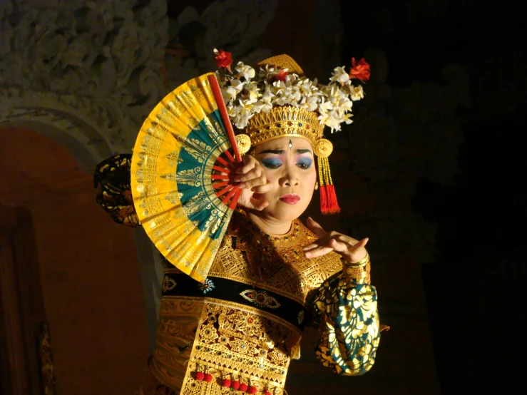 a woman in costume holding a yellow fan