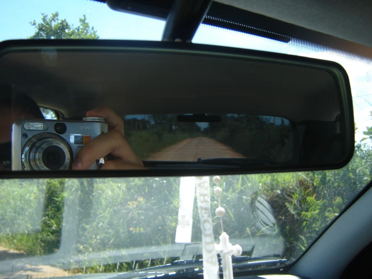 the reflection of a person taking a po in the side mirror of a vehicle