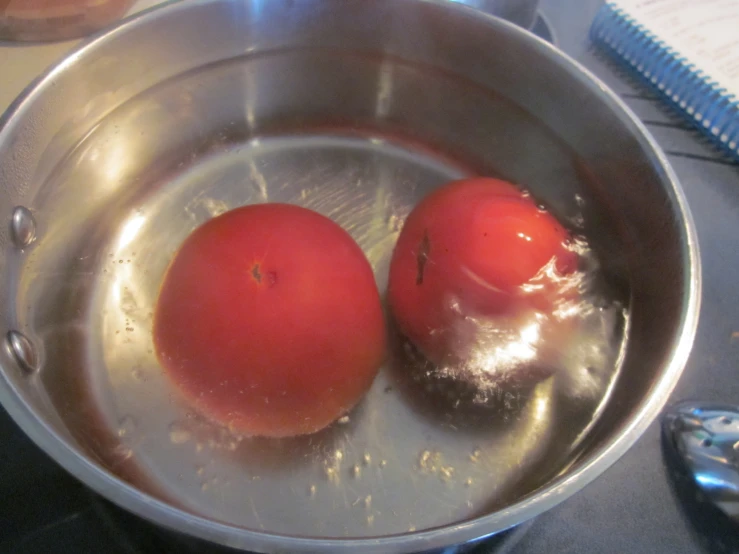 two tomato halves that are in water sitting on the stove