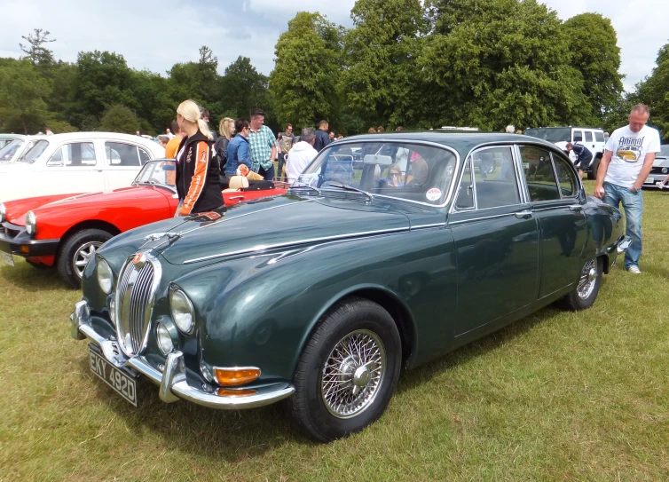 a vintage green car parked in a field