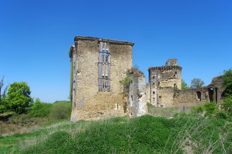 an old stone building on top of a green hill