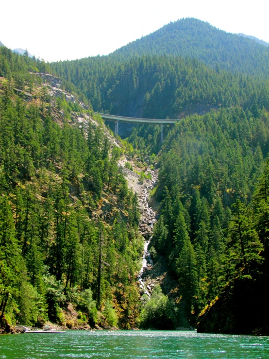 a bridge near some mountains in a green mountain