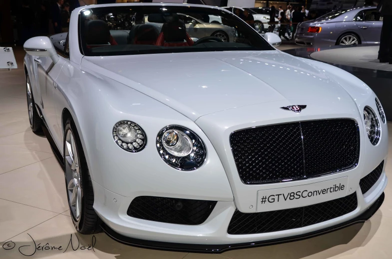 a white bentley is parked in a building