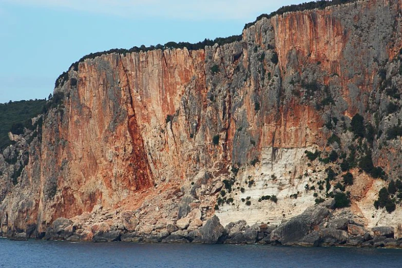 an orange cliff above a body of water