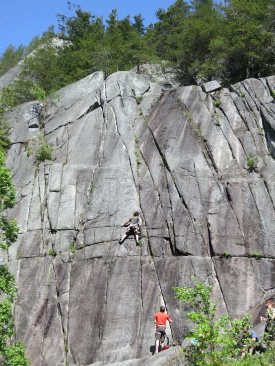 a couple people climbing on the side of a large rock