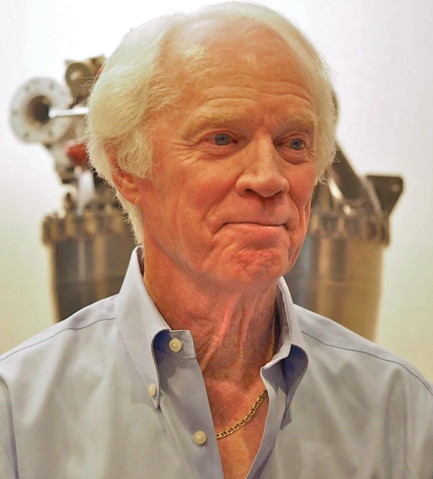 a man in a shirt and collared shirt with a clock on the wall