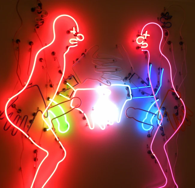 a neon sign in front of two people