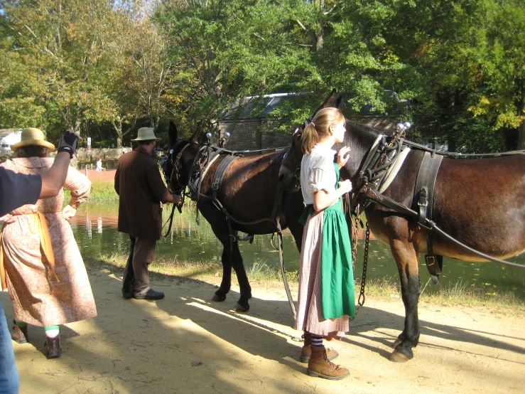 two girls standing next to two horses on a road