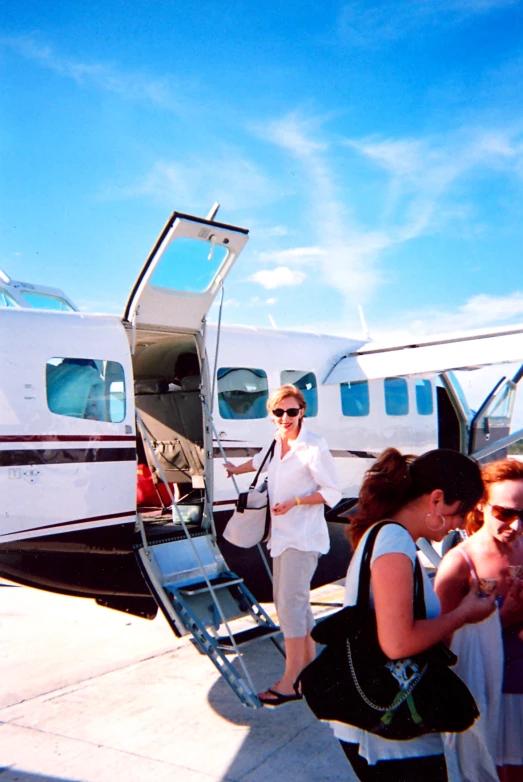 the woman is stepping off the plane with two other people near by