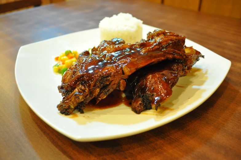 the bbq ribs are served on the plate with rice and corn