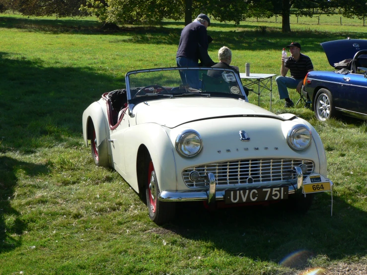 people sit at tables and talk to a classic car