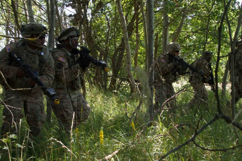 several soldiers walking through a forest in camouflage