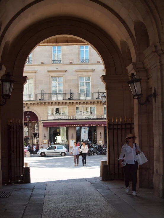 people walk down an arched stone walkway near an open archway