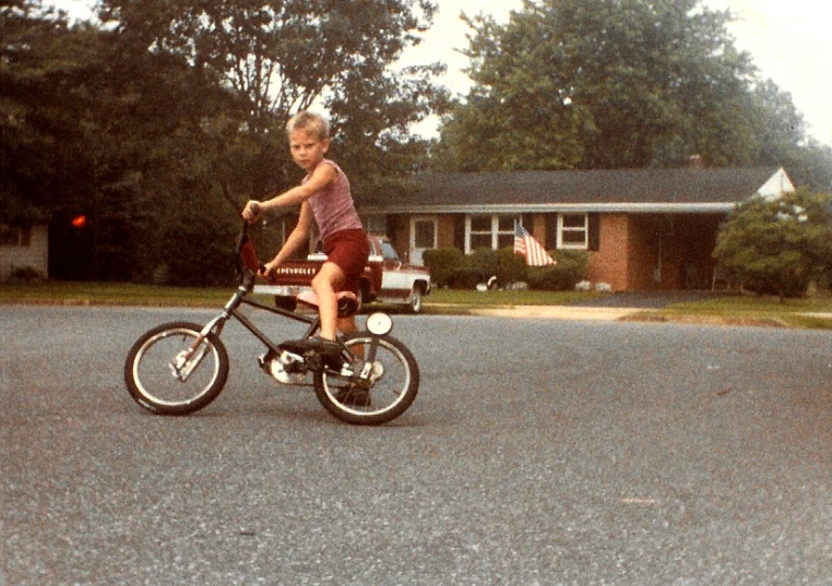 the small child rides a bicycle in the driveway