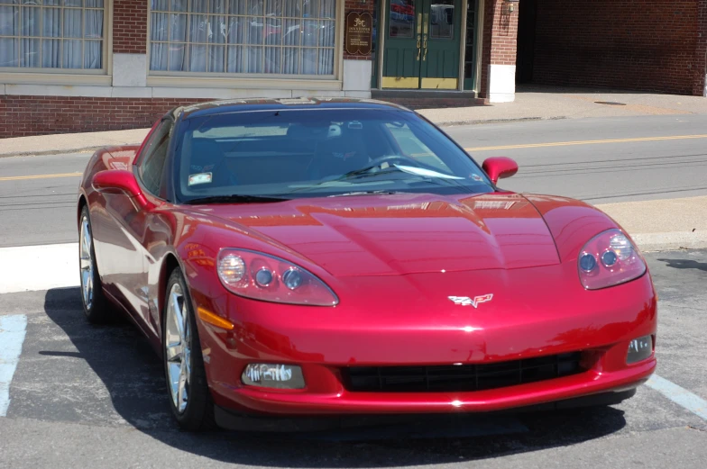 a red sports car parked on the street in front of a brick building