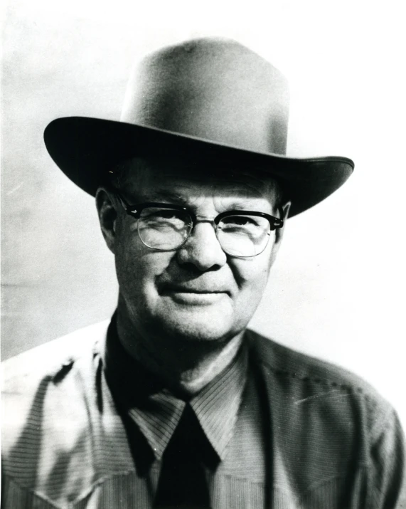 man in a hat and eyeglasses poses for a picture