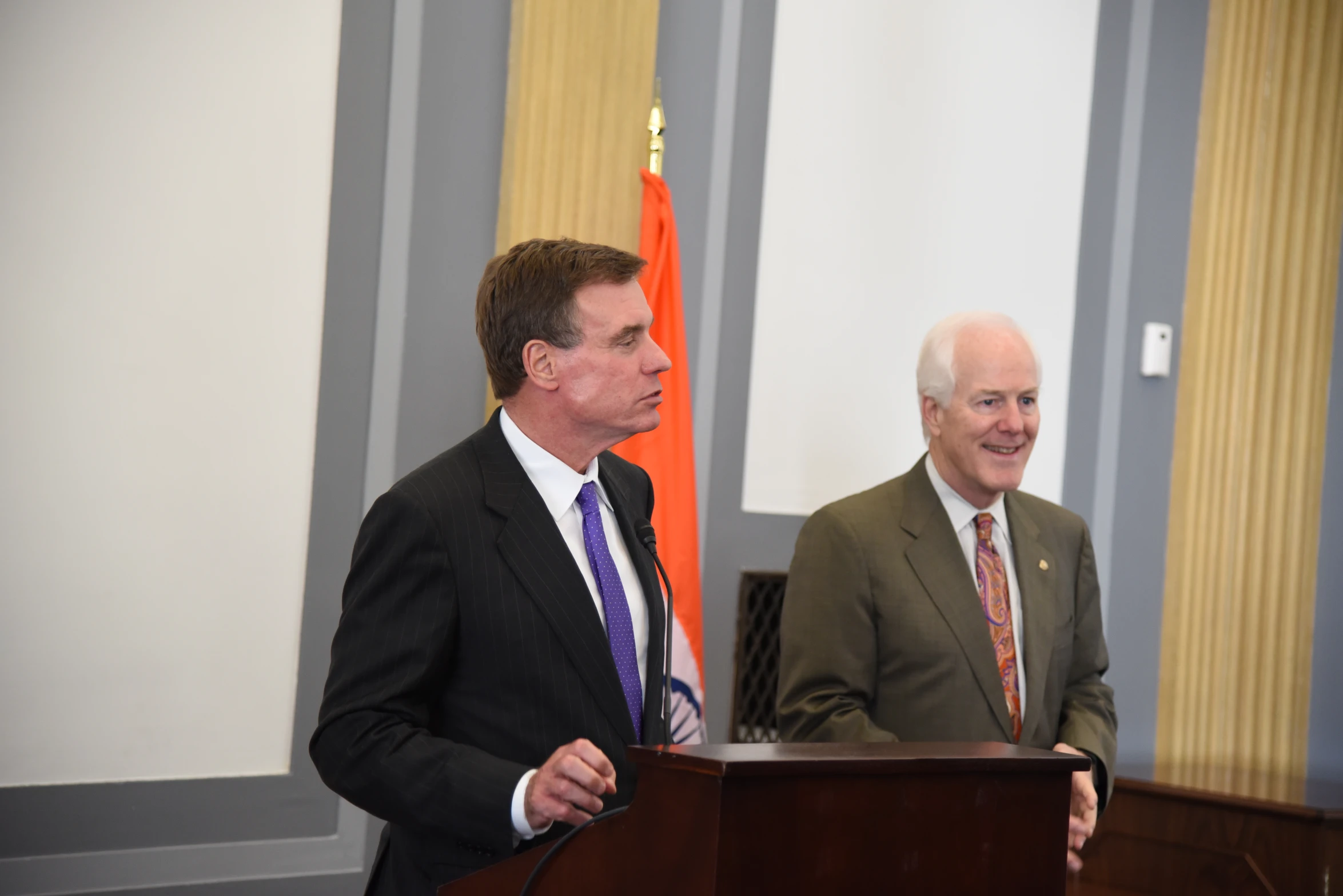 two men in suits are talking while standing next to each other