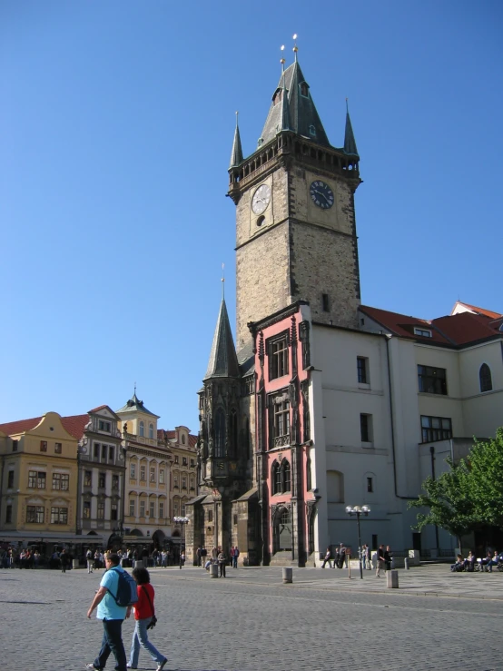 people are walking through a square in front of a clock tower