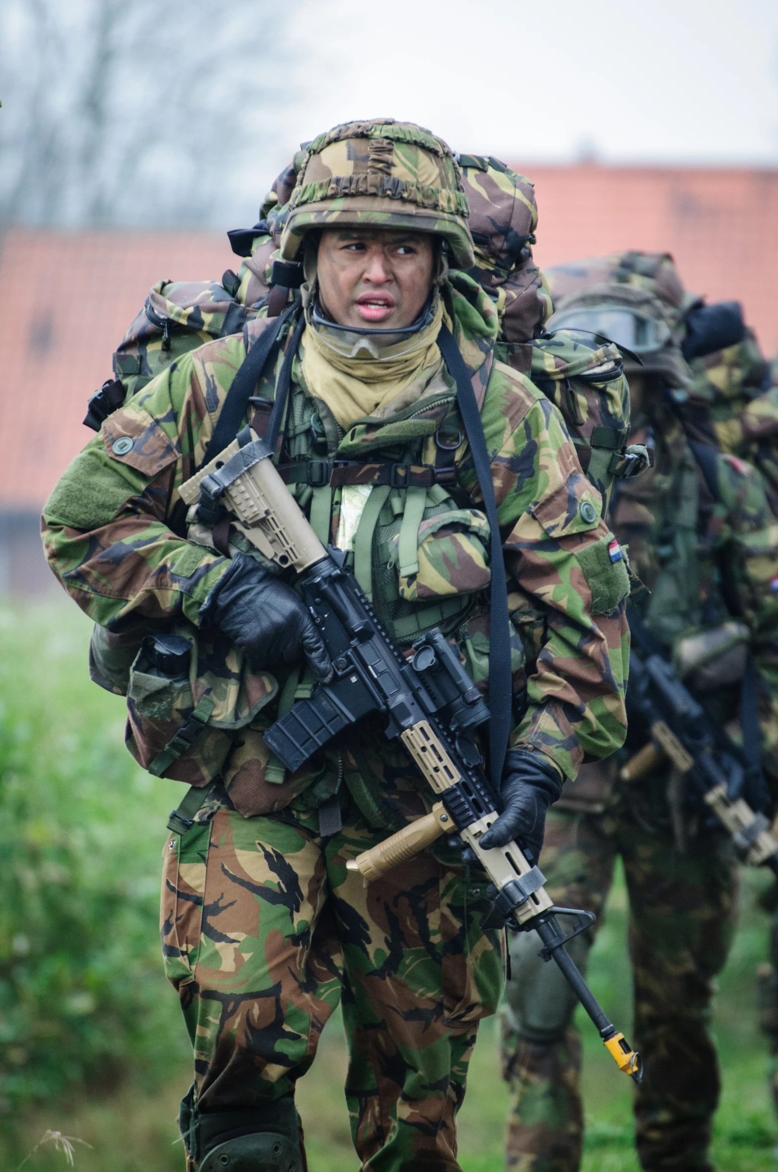 a man in camouflage walking along side other men with guns