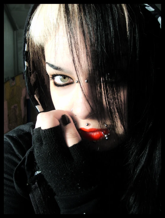 a girl wearing black with piercing and a red lip
