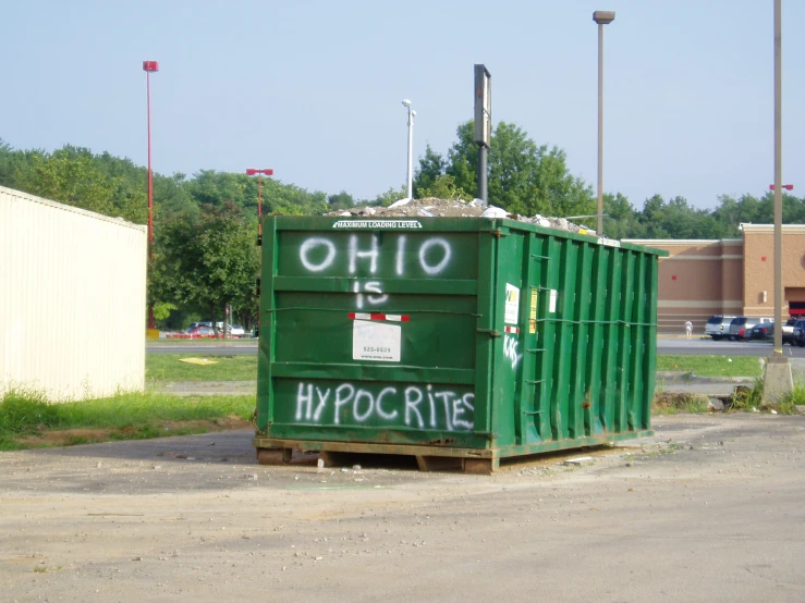 an old green dumpster on the side of a road