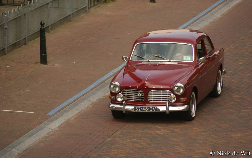 an old car driving down the street during the day