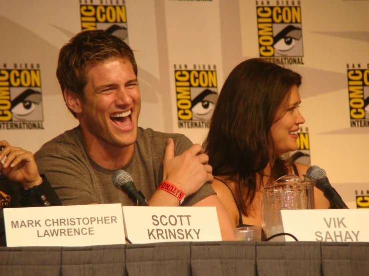 a man and woman sitting at a table laughing