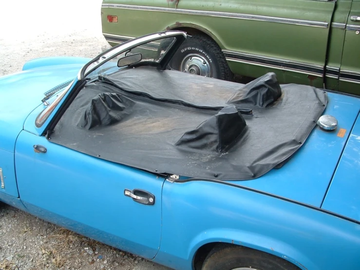 a very old blue car that has a bag on top of it